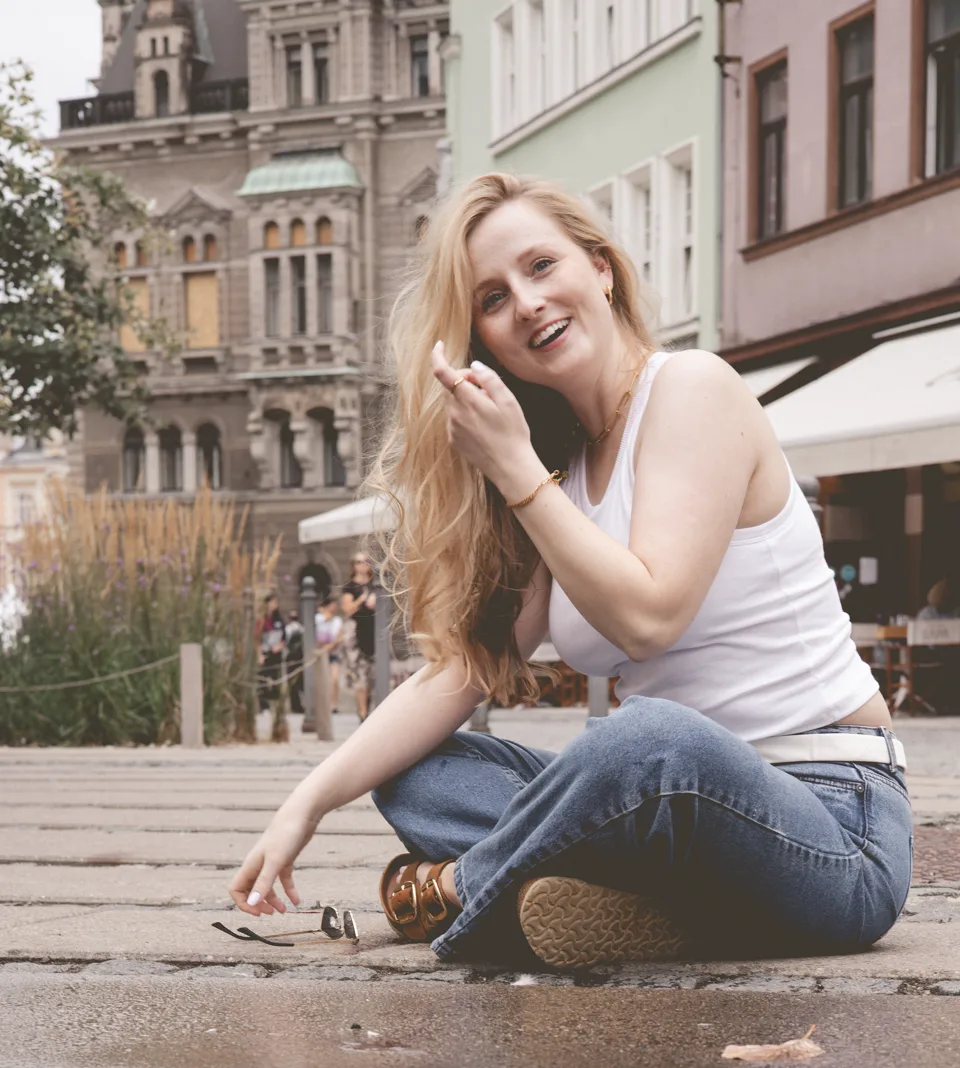 Usmívající se žena sedící na dlažbě městského náměstí